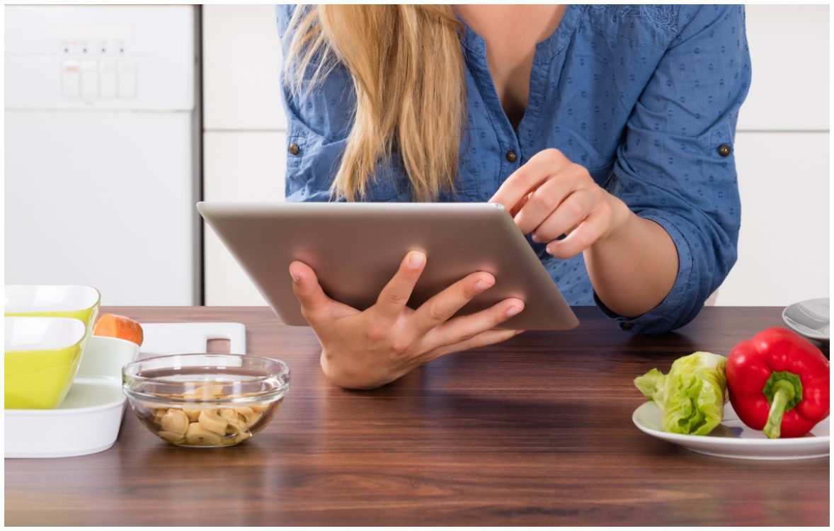 women leaning on countertop holding tablet
