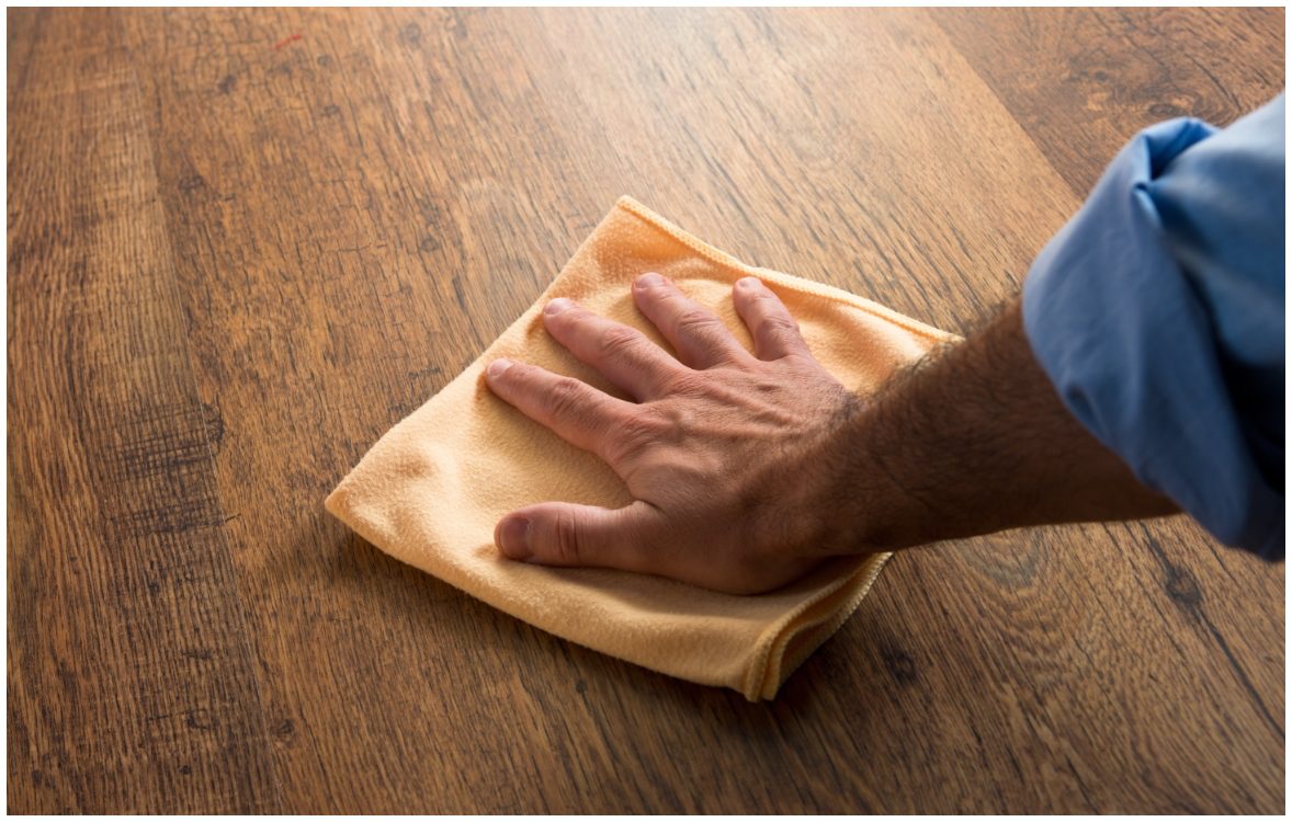 male hand holding towel on wood floor